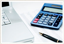 Photo of calculator, laptop, pen and a sheet of figures